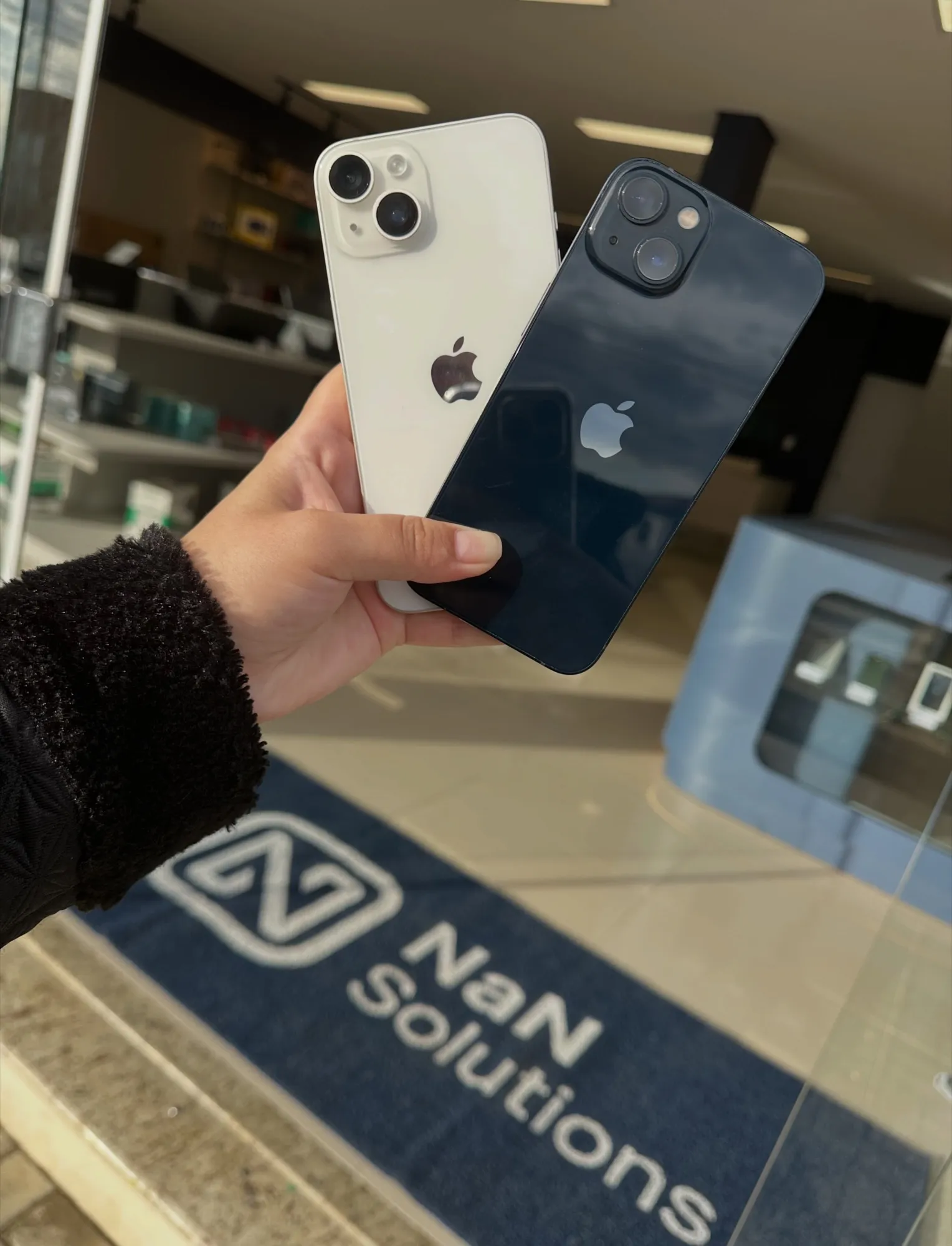 Dois iPhones na mão em frente à entrada da loja da NaN Solutions